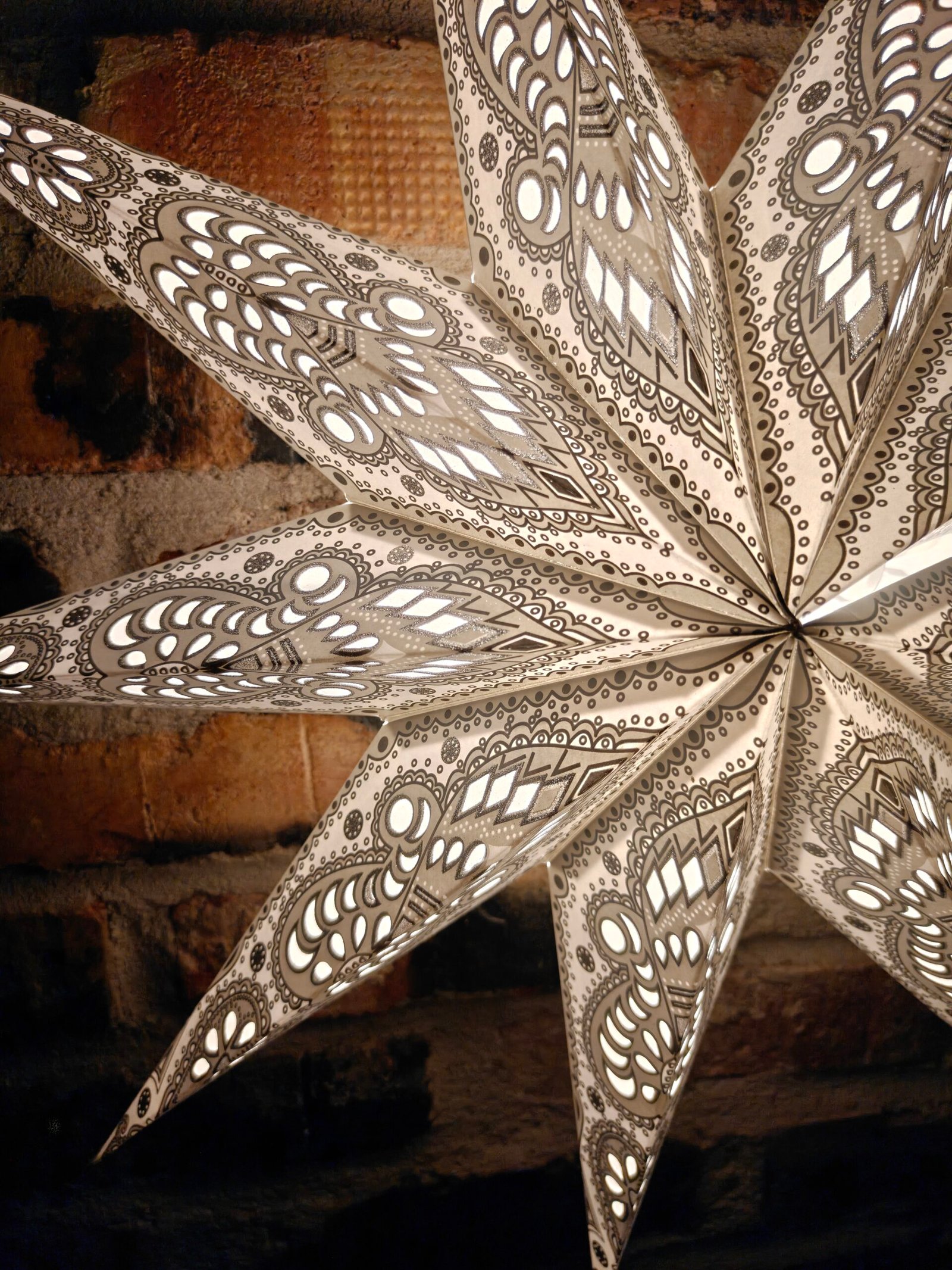 40. Vit Julstjärna 9 armar tänd närbild Hängande julstjärna i papper, adventsstjärna för fönster med dekorativt mönster.