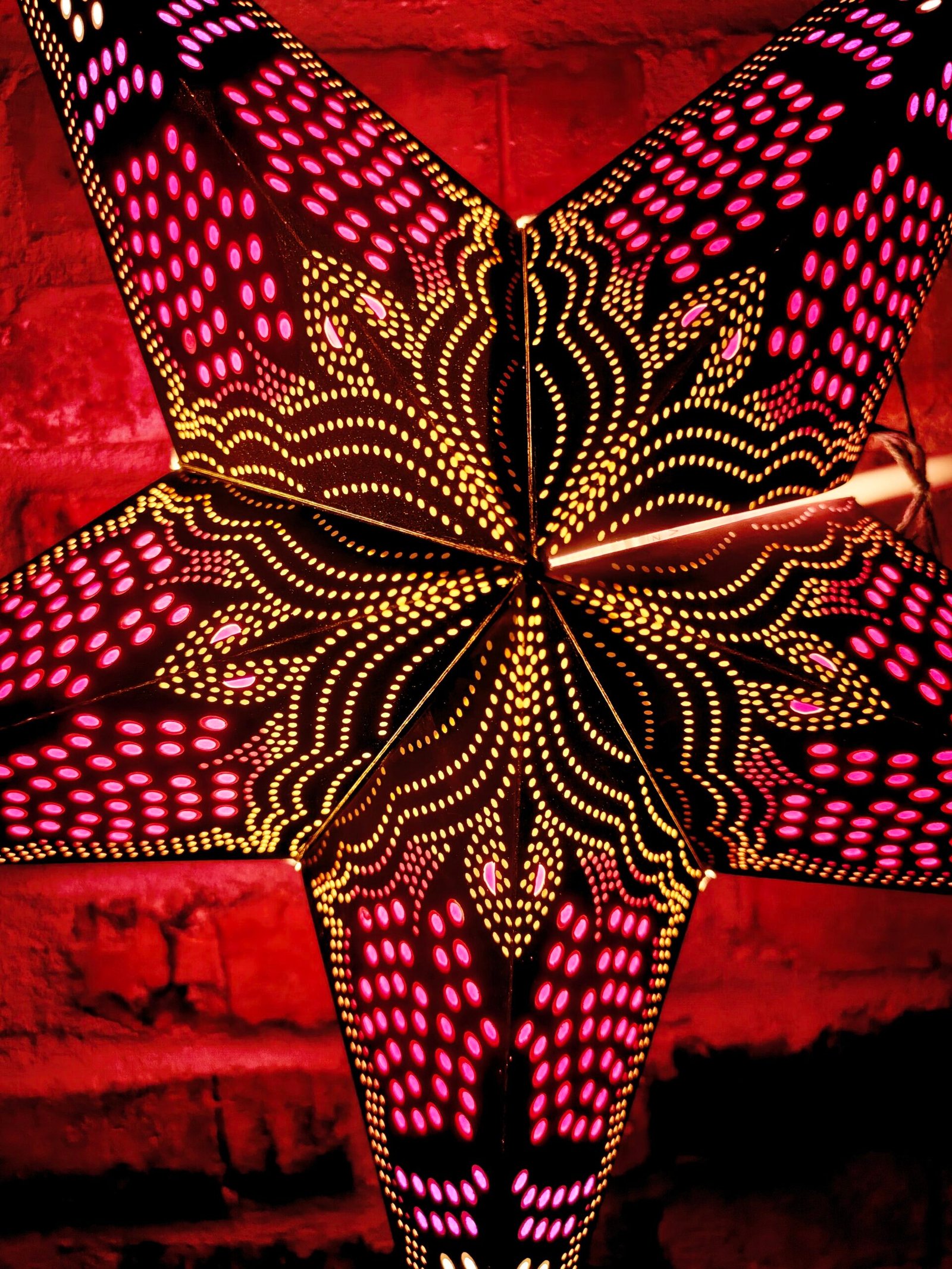 41. Julstjärna svartprickig tänd närbild Hängande julstjärna i papper, adventsstjärna för fönster med dekorativt mönster.
